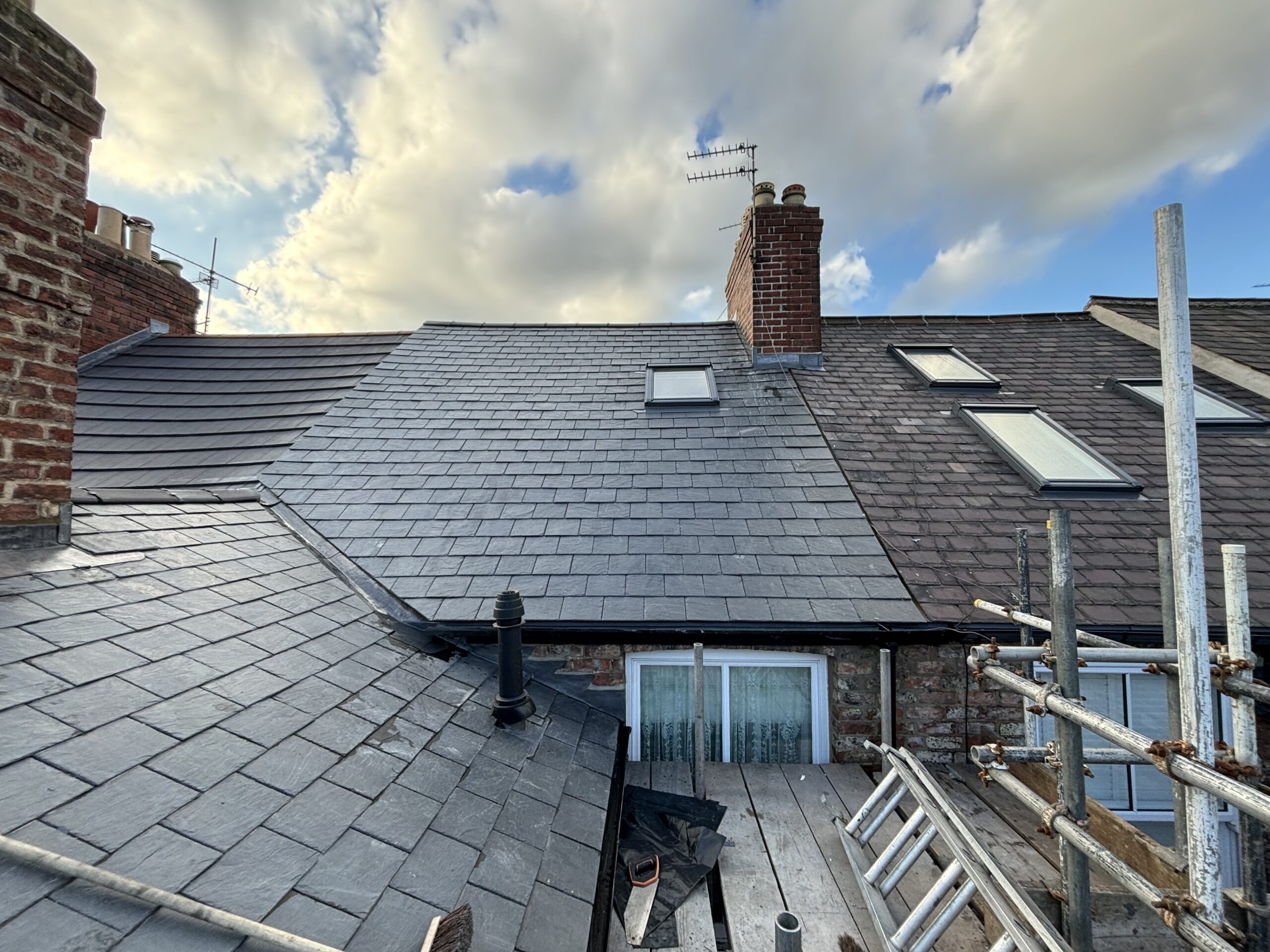 Completed slate roof on a British terraced house with neat grey tiles